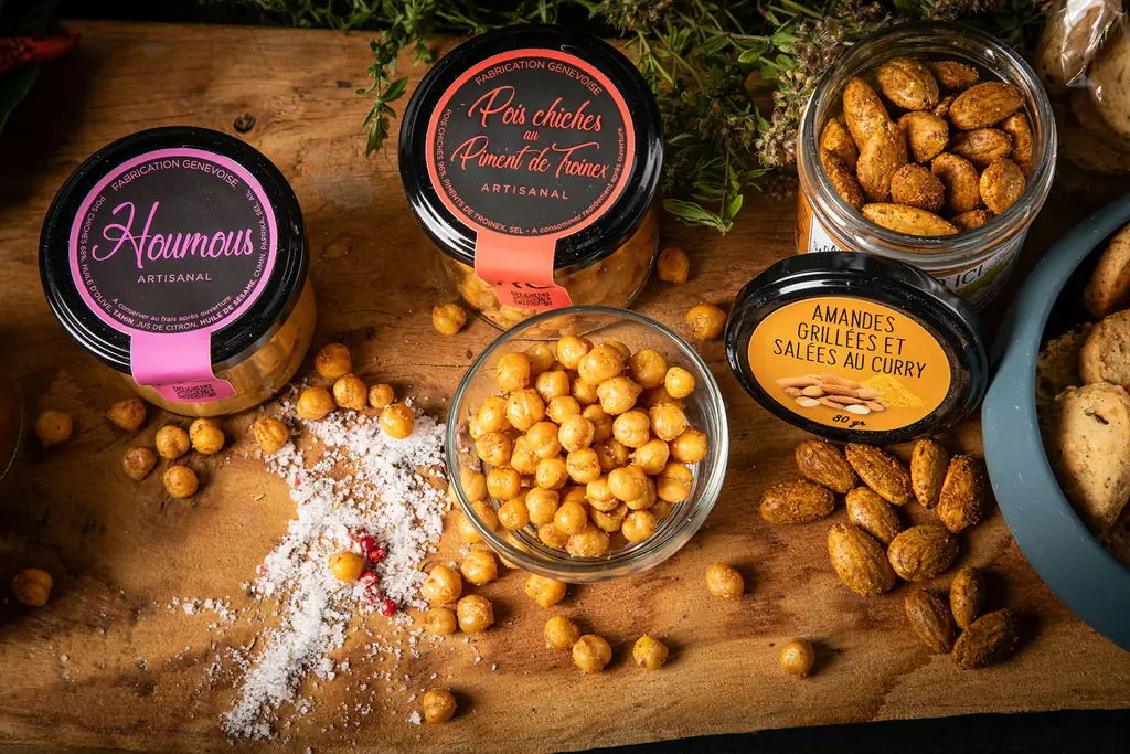 Houmous, pois chiches grillés et amandes salées au curry sur une planche en bois