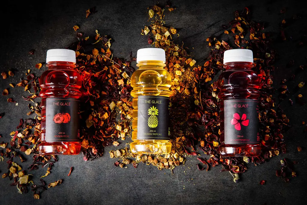 Trois bouteilles d'infusion glacée entourées de fruits et de fleurs séchés