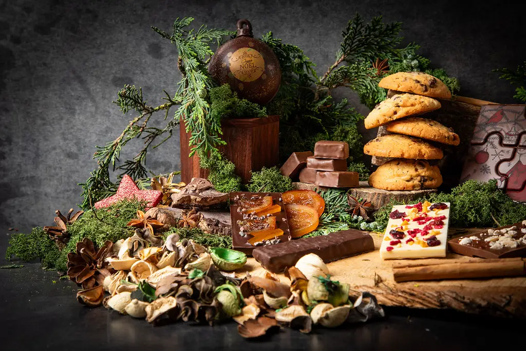 Cookies, chocolats et fleurs séchées parmi des branches de sapin